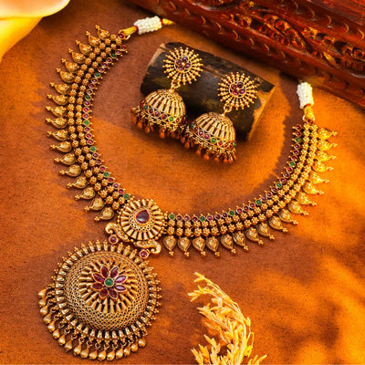Temple necklace and earrings on a textured brown surface