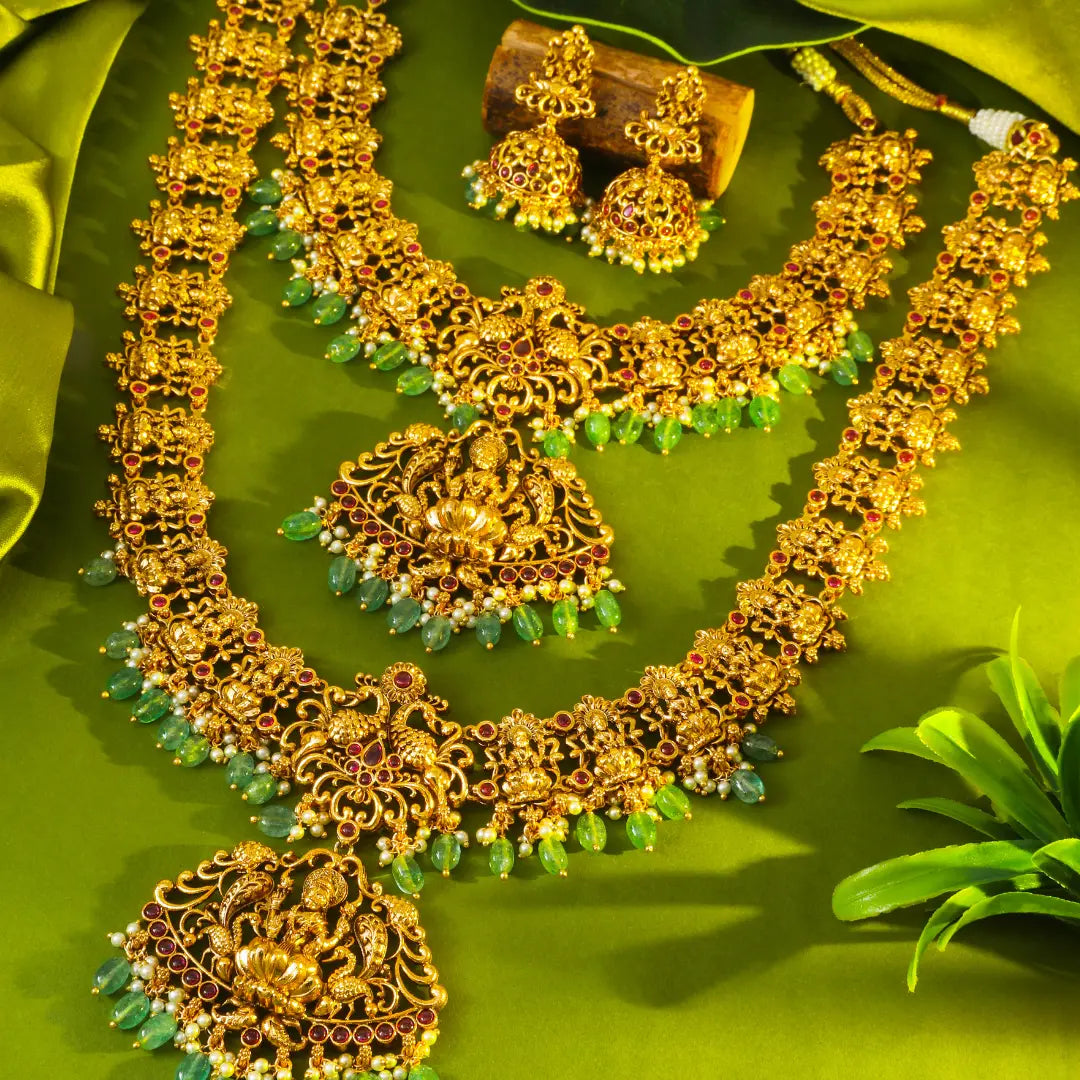Lakshmi Gold necklace with green stones and matching earrings on a green background