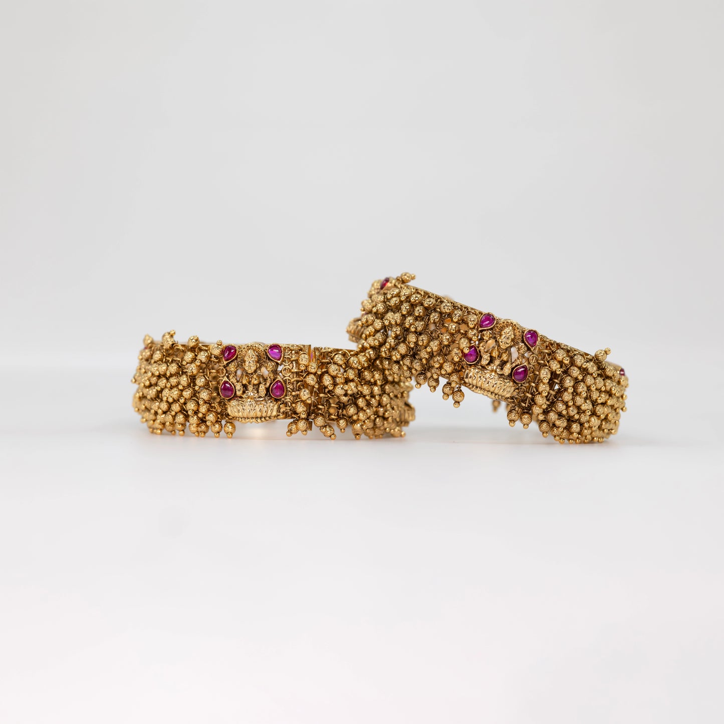 Gold Ball Bangle with red gemstones on a textured surface