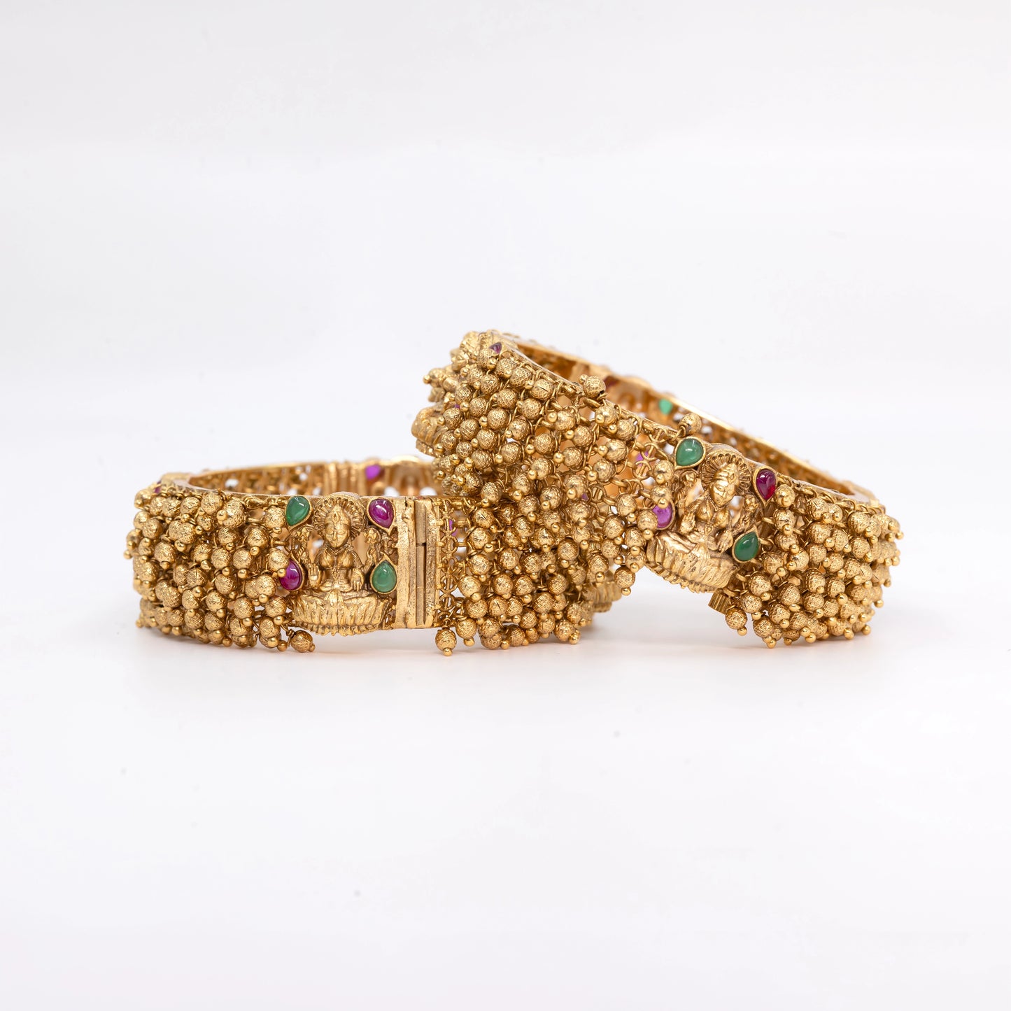 Gold Ball Bangle with red-green gemstone on a textured surface