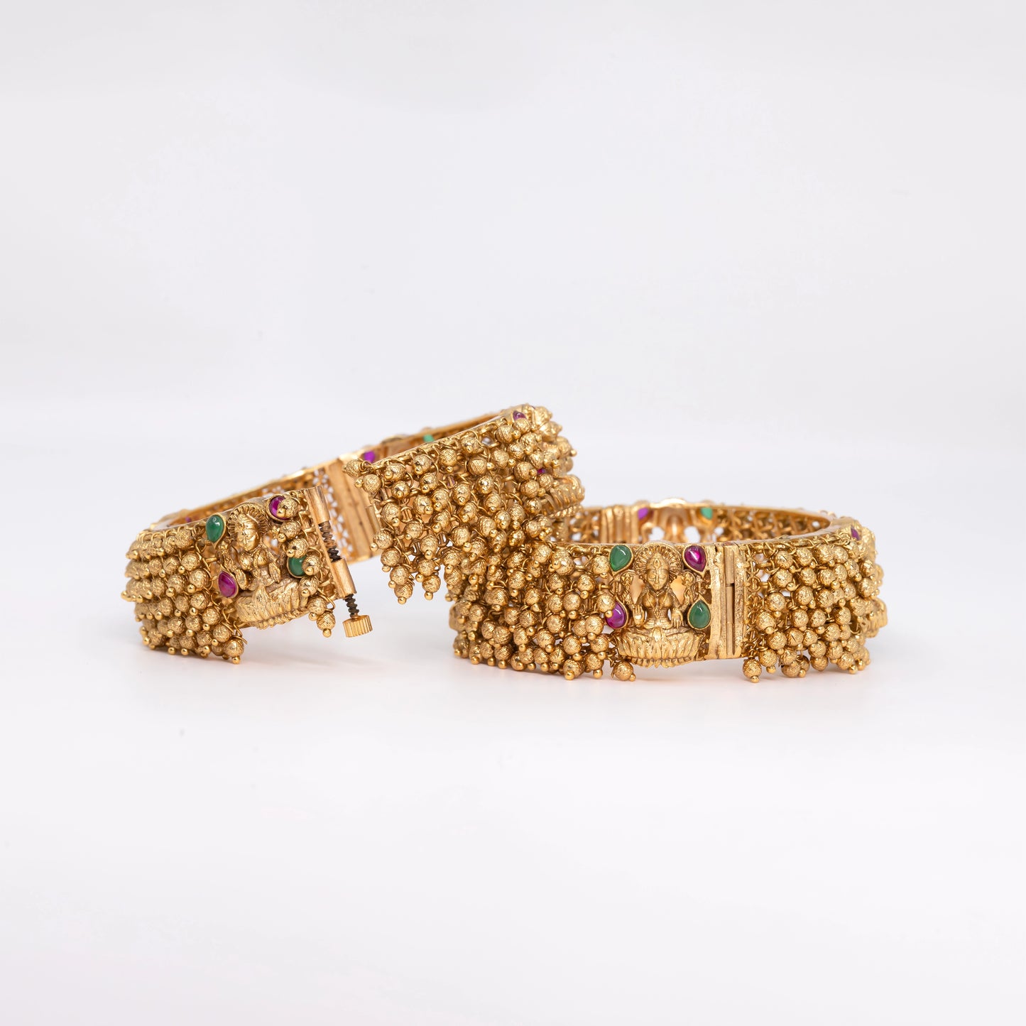 Gold Ball Bangle with red-green gemstone on a textured surface