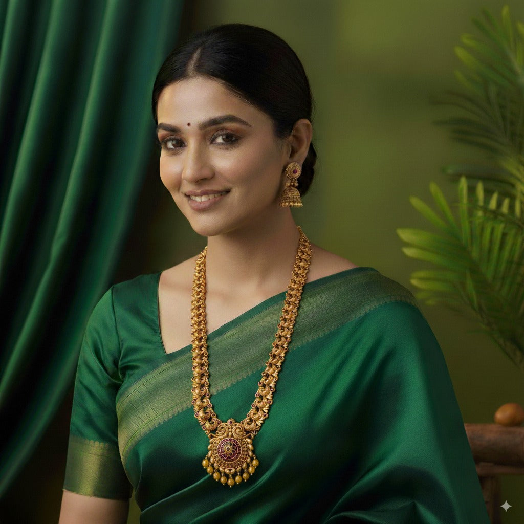 Woman wearing a green saree with gold jewelry against a green background