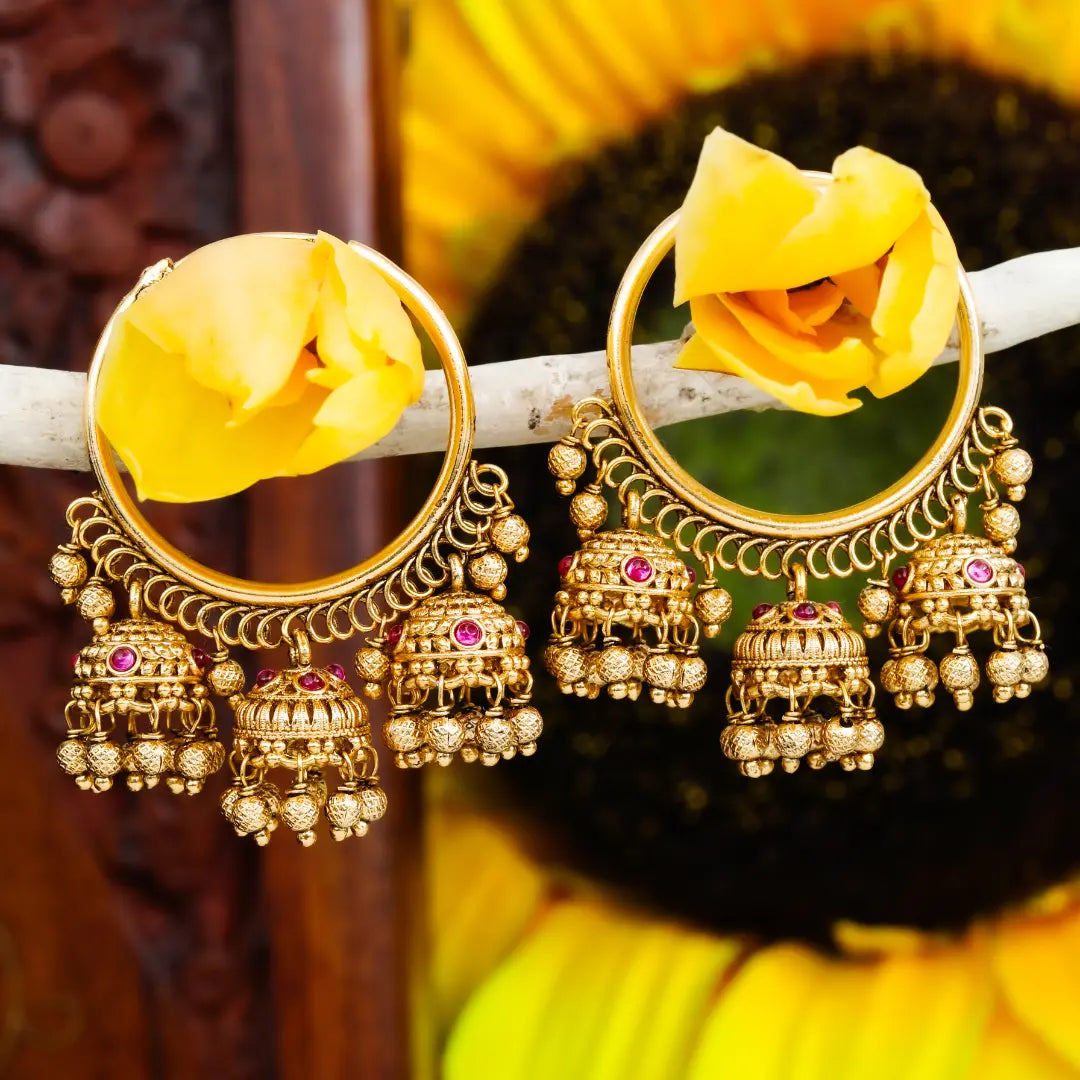 Gold earrings with intricate designs and yellow flowers on a dark background